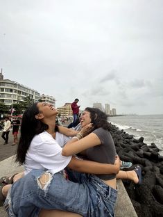 two women sitting on the edge of a pier