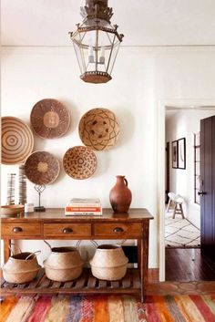 a room with many baskets on the wall and a table in front of an open door