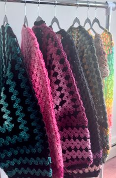 four crocheted scarves hanging on a rack