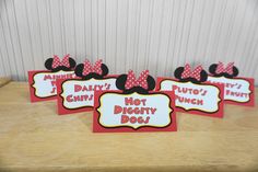 four red and black mickey mouse place cards on a wooden table with white wall in the background