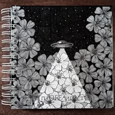 a spiral notebook with flowers and an alien ship in the sky on top of it