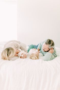 an older man and two young children laying on top of a bed with white sheets