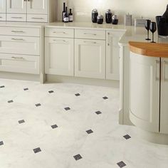 a kitchen filled with lots of white cabinets and counter top covered in black and white tile