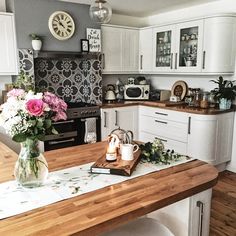 a kitchen filled with lots of white cabinets and counter top next to a wooden bar