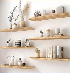 three wooden shelves with plants, books and other decorative items on them against a white wall