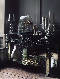 an ornate console table with vases, candles and other decorative items on it in a dark room