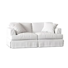 a white couch with two pillows on it and one pillow is folded over the back