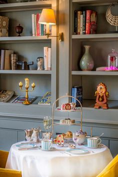 a table with two plates and cups on it in front of some bookshelves