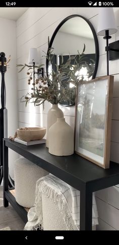 a black table topped with a mirror and vase filled with flowers on top of it