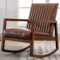 a brown leather rocking chair sitting on top of a rug in front of a window