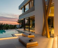 a modern house with an outdoor pool and lounge chairs at dusk, overlooking the ocean