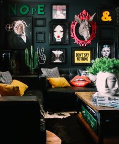 a living room with black walls and pictures on the wall, couches and tables