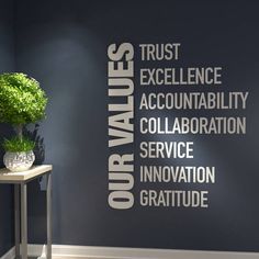 a black wall with white lettering on it and a plant in the corner next to it