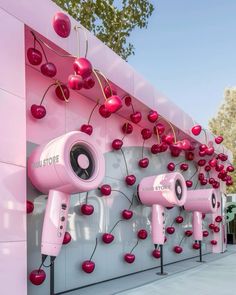 pink hair dryers on display in front of a wall with cherries hanging from it