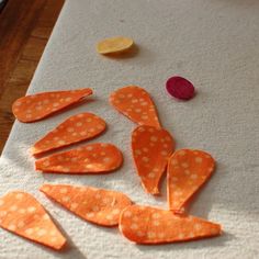 several pieces of orange and white polka dot paper on a wooden table with some scissors