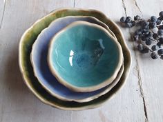 three bowls are stacked next to each other on a table with blackberries in the background