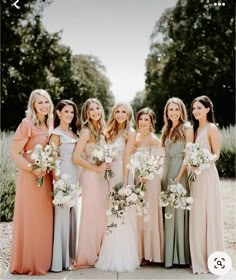 a group of women standing next to each other wearing dresses and holding bouquets in their hands