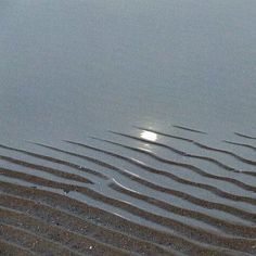 the sun shines brightly in the water as it reflects on the sand