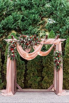 an outdoor wedding arch decorated with flowers and greenery