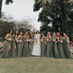 a group of women standing next to each other on top of a grass covered field