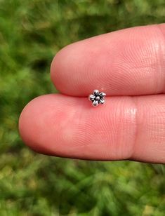 a person's hand holding a tiny diamond ring in their left hand, with grass in the background