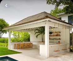 a gazebo with an outdoor kitchen and dining area in the back ground next to a swimming pool