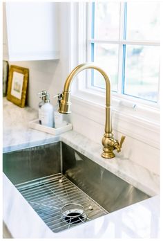 a kitchen sink under a window next to a faucet