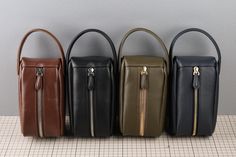 four different colored leather handbags lined up in a row on a tiled floor, with one being opened and the other is closed