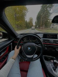 a woman driving a car on the road with her hands on the steering wheel and dashboard