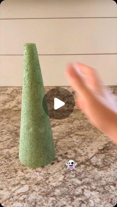 a person is playing with a green cone on the counter next to a cat toy