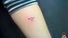 a woman's arm with a small tattoo that reads o and has the letter o on it