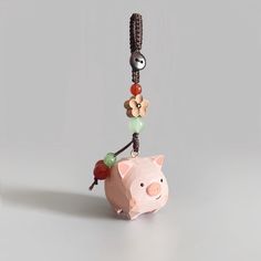 a pink pig is hanging from a string with beads on it's back end