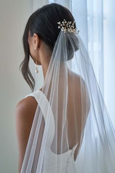 a woman wearing a wedding veil with flowers on her head and hair comb in the other hand