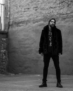 a man standing in front of a brick wall