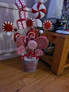 a bucket filled with lollipops and candy canes on top of a wooden table