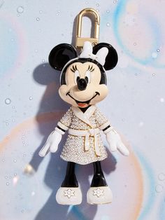 a mickey mouse keychain hanging on a wall with water droplets in the background