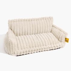 a white dog bed that is shaped like a couch and has a yellow tag on it