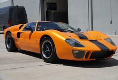 an orange sports car parked in front of a building