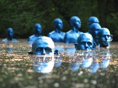 there are many blue statues in the water and one is swimming with it's head submerged