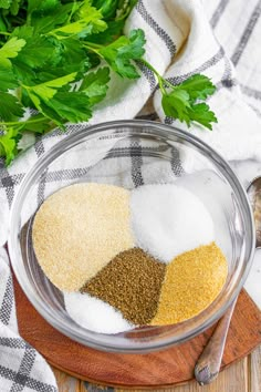 herbs and seasonings in a glass bowl on a cutting board next to parsley