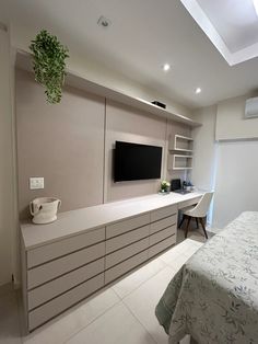 a bedroom with a bed, desk and television on the wall in front of it