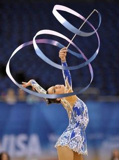 a woman in a blue and white outfit is holding a ribbon around her neck while standing on a basketball court