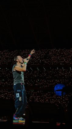 a man standing on top of a stage with his arms outstretched in front of him