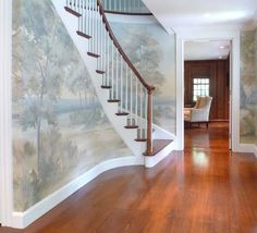 a staircase painted with trees on the wall next to a wooden floor and white railing