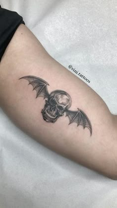 a skull and bat tattoo on the arm