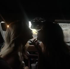 two women sitting in the back seat of a car with their heads turned to look at each other