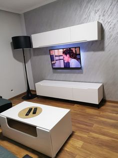 a flat screen tv sitting on top of a white entertainment center next to a black lamp