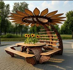 a wooden table and bench with sunflowers in the center on a brick patio