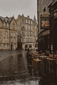 an empty street with tables and chairs in the rain