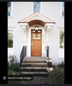 a white house with a brown door and steps leading up to the front entrance area